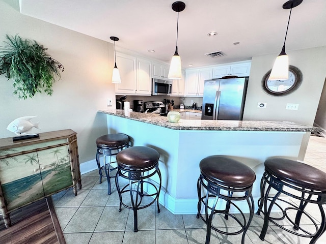 kitchen featuring white cabinets, appliances with stainless steel finishes, kitchen peninsula, and stone counters