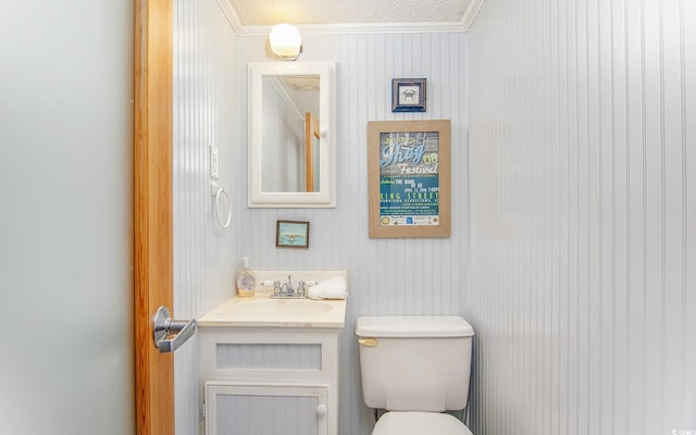 bathroom with toilet, vanity, a textured ceiling, and ornamental molding