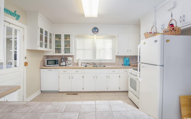 kitchen with backsplash, white appliances, sink, light tile patterned floors, and white cabinetry