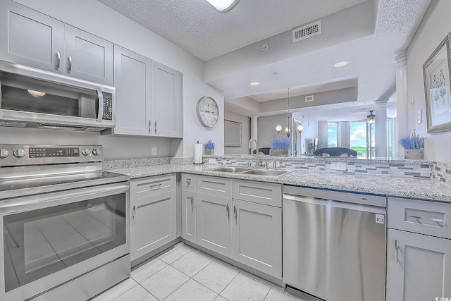 kitchen featuring kitchen peninsula, sink, a textured ceiling, and appliances with stainless steel finishes