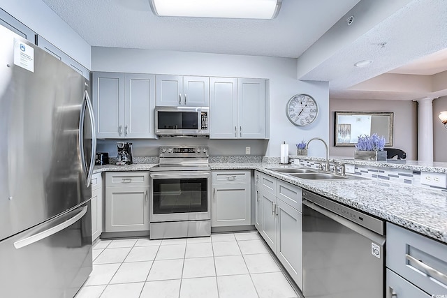 kitchen with a textured ceiling, stainless steel appliances, sink, light tile patterned floors, and gray cabinets