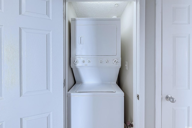 washroom with stacked washer and dryer and a textured ceiling