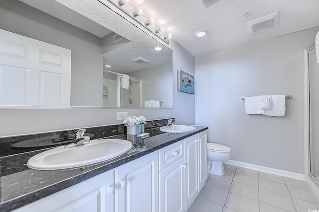 bathroom featuring tile patterned floors, vanity, a textured ceiling, toilet, and a shower with shower door