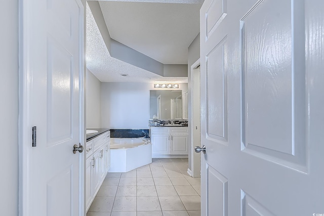 bathroom with tile patterned floors, a bathtub, vanity, and a textured ceiling