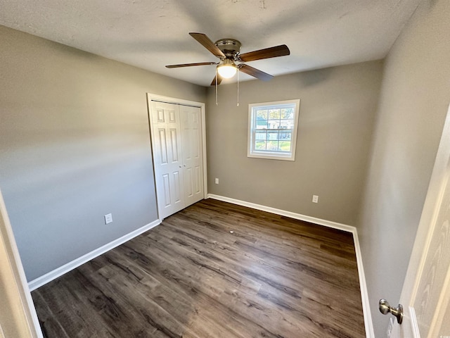 unfurnished bedroom featuring ceiling fan, dark hardwood / wood-style floors, and a closet