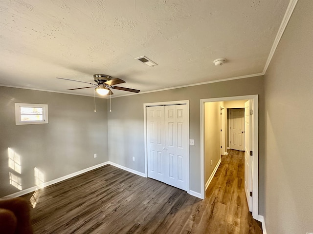 unfurnished bedroom featuring ceiling fan, ornamental molding, dark wood-type flooring, and a closet