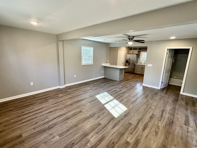 unfurnished living room featuring plenty of natural light, ceiling fan, and dark hardwood / wood-style flooring