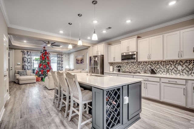 kitchen with stainless steel appliances, light countertops, visible vents, light wood-style flooring, and open floor plan