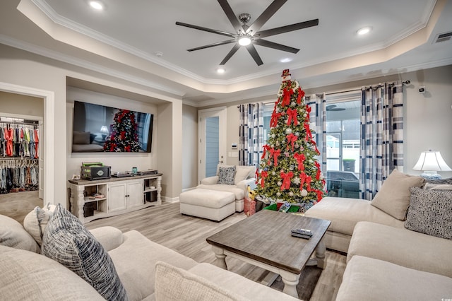 living area with light wood-style floors, a tray ceiling, ornamental molding, and recessed lighting