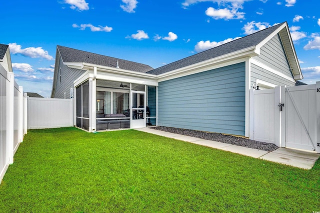 back of house featuring a garage, a lawn, a sunroom, a fenced backyard, and a gate