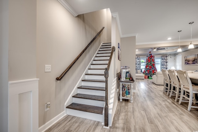 stairs with ornamental molding, wood finished floors, a ceiling fan, and baseboards