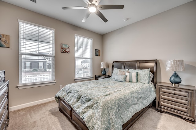 bedroom featuring light colored carpet, ceiling fan, and baseboards