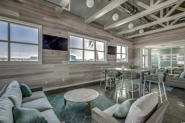 living room featuring lofted ceiling with beams, finished concrete floors, and wooden walls