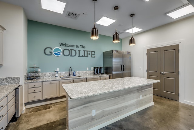 kitchen featuring visible vents, a center island, stainless steel built in refrigerator, concrete floors, and a sink