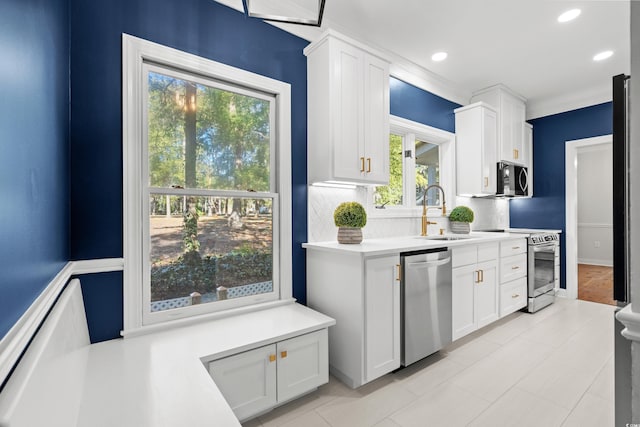 kitchen featuring decorative backsplash, appliances with stainless steel finishes, sink, light tile patterned floors, and white cabinets