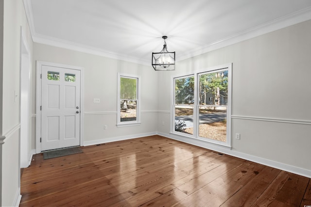 unfurnished dining area featuring a chandelier, hardwood / wood-style floors, and ornamental molding