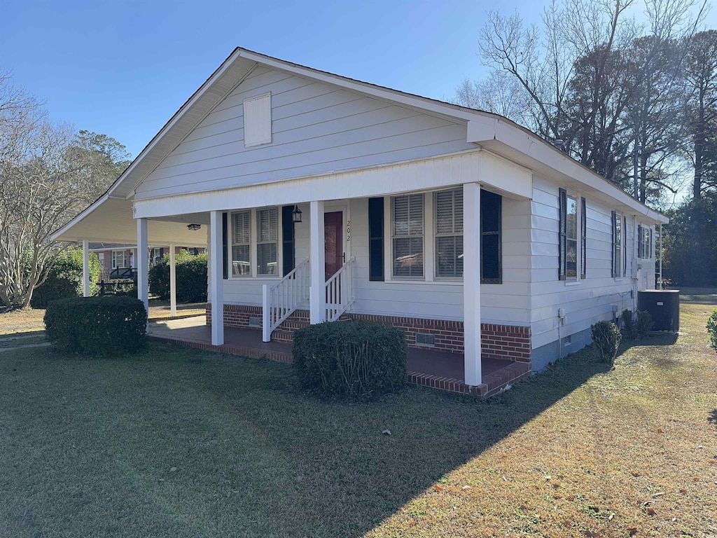 view of front of property with covered porch, central air condition unit, and a front lawn