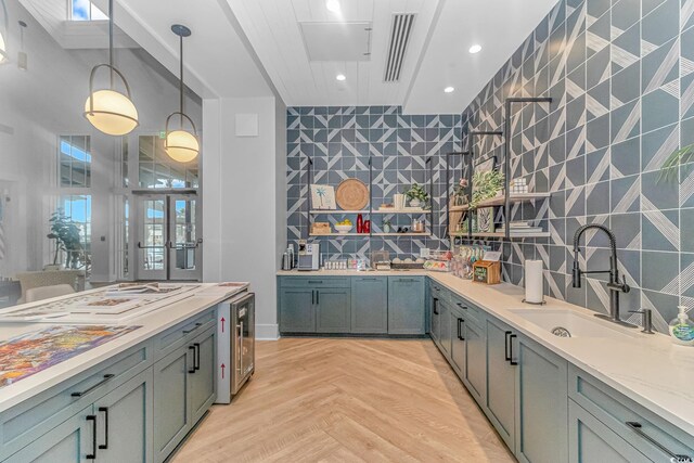 kitchen featuring decorative light fixtures, sink, backsplash, beverage cooler, and light parquet flooring