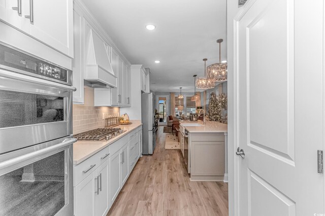 kitchen featuring sink, white cabinetry, a center island with sink, appliances with stainless steel finishes, and pendant lighting