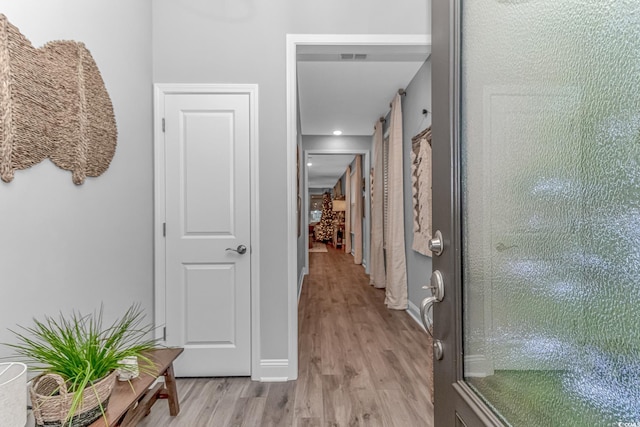 hall with light wood-style floors and baseboards