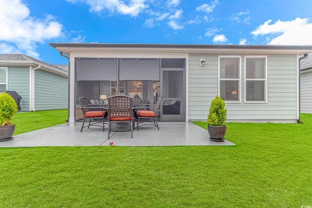 back of property with a patio area, a sunroom, and a lawn