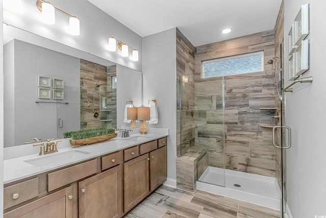 bathroom with a sink, a shower stall, and double vanity