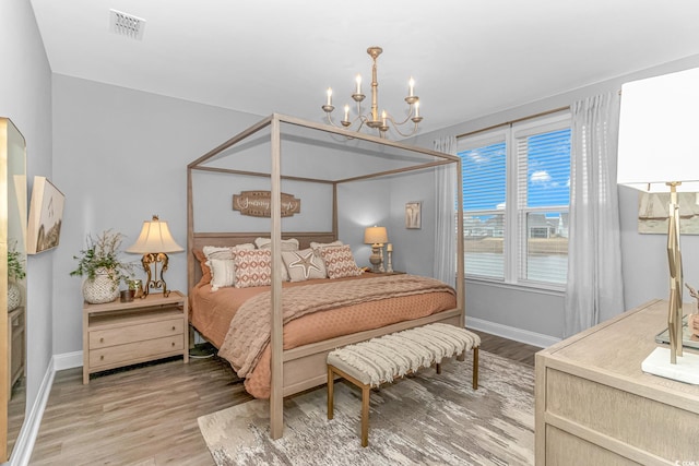 bedroom featuring a chandelier, wood finished floors, visible vents, and baseboards