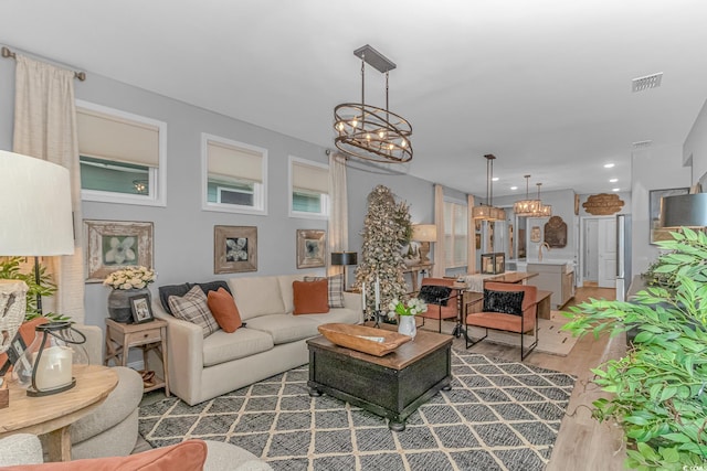 living area with recessed lighting, wood finished floors, visible vents, and a notable chandelier