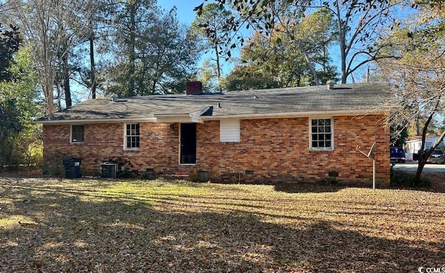 rear view of house with central air condition unit and a yard