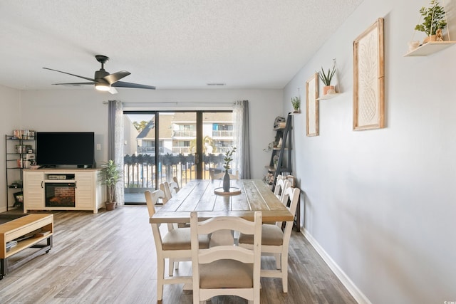 dining area featuring hardwood / wood-style floors, ceiling fan, and a textured ceiling