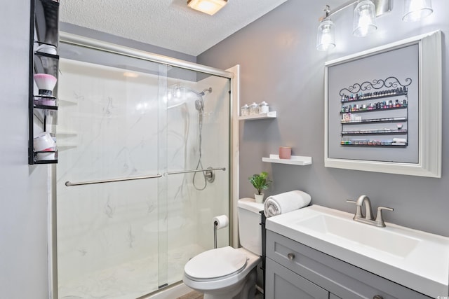 bathroom featuring vanity, toilet, a shower with door, and a textured ceiling