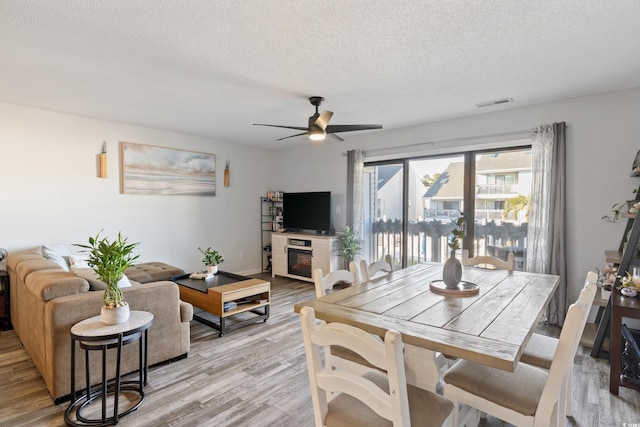 dining room with ceiling fan, a textured ceiling, and light hardwood / wood-style flooring