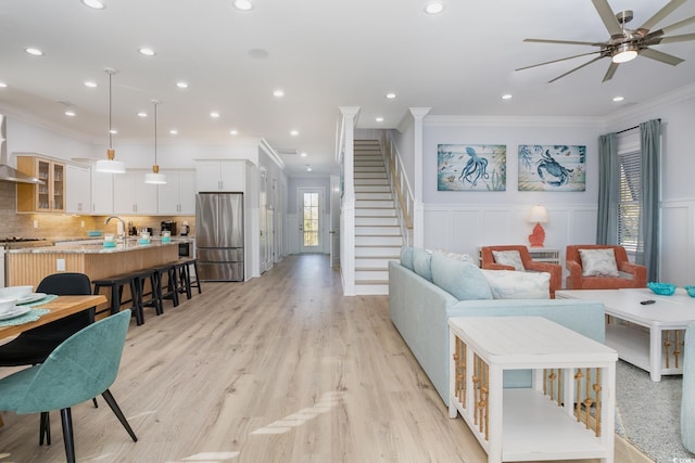 living room featuring ceiling fan, light hardwood / wood-style flooring, and ornamental molding