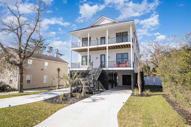 beach home featuring a carport, covered porch, a balcony, and a front yard