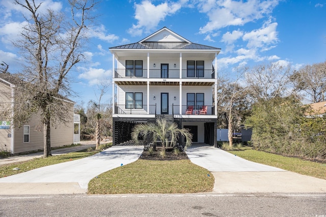 raised beach house featuring a front lawn, a balcony, and a carport