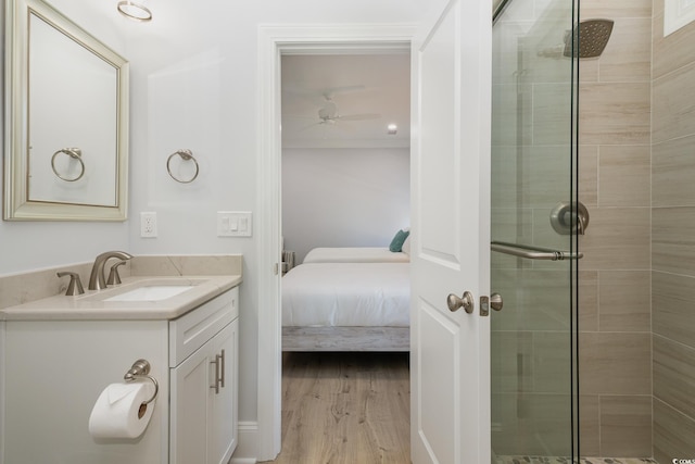 bathroom with ceiling fan, a shower with door, vanity, and hardwood / wood-style flooring