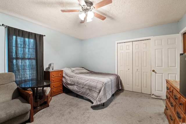 carpeted bedroom with a textured ceiling, a closet, and ceiling fan