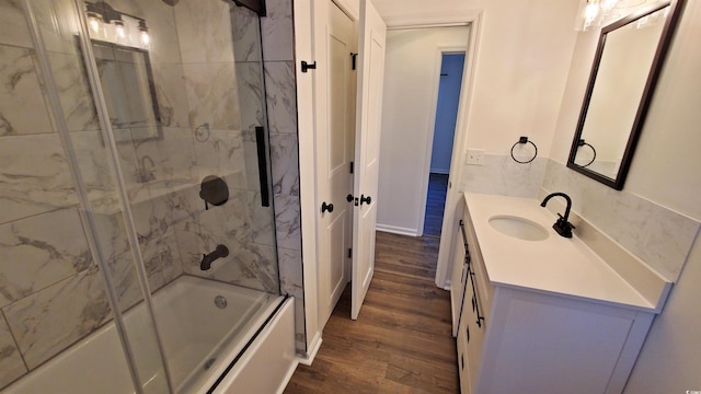 bathroom featuring hardwood / wood-style flooring, vanity, and bath / shower combo with glass door