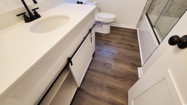 full bathroom with hardwood / wood-style floors, vanity, toilet, and combined bath / shower with glass door