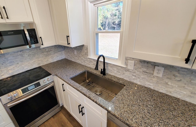 kitchen with light stone countertops, sink, decorative backsplash, white cabinets, and appliances with stainless steel finishes