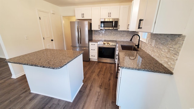 kitchen featuring white cabinetry, sink, stainless steel appliances, dark hardwood / wood-style floors, and dark stone countertops