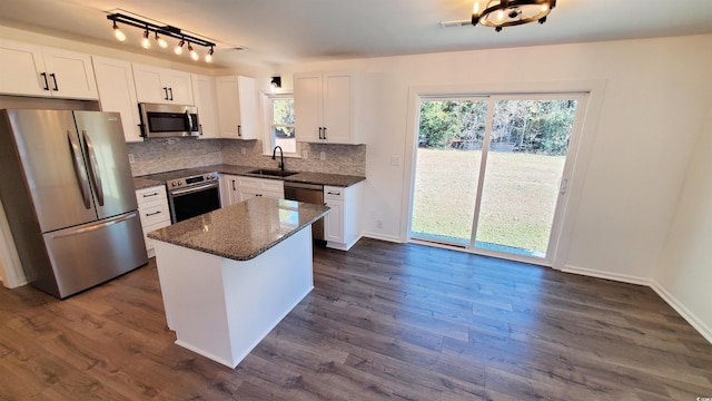 kitchen with a center island, sink, dark stone countertops, white cabinetry, and stainless steel appliances