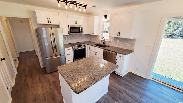 kitchen featuring a center island, dark stone counters, sink, white cabinetry, and stainless steel appliances