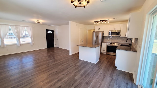 kitchen with appliances with stainless steel finishes, tasteful backsplash, sink, white cabinets, and a center island