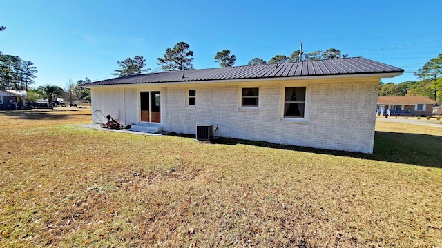 back of house featuring central AC unit and a lawn