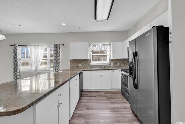 kitchen with white cabinetry, appliances with stainless steel finishes, kitchen peninsula, and sink