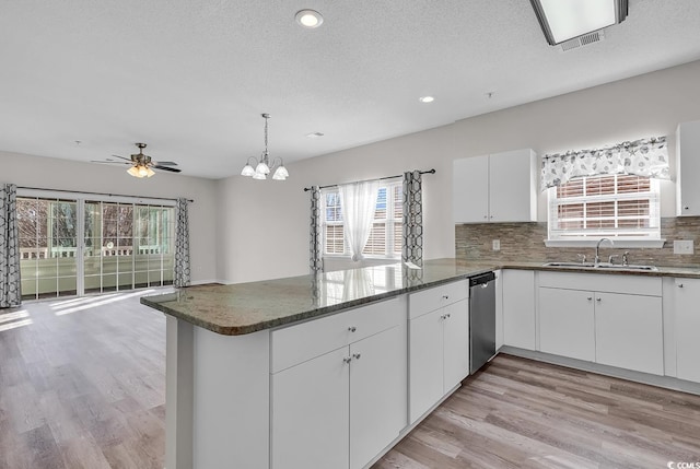 kitchen featuring white cabinets, decorative backsplash, ceiling fan with notable chandelier, and sink