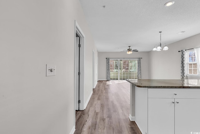 kitchen featuring a wealth of natural light, a textured ceiling, white cabinetry, and hanging light fixtures