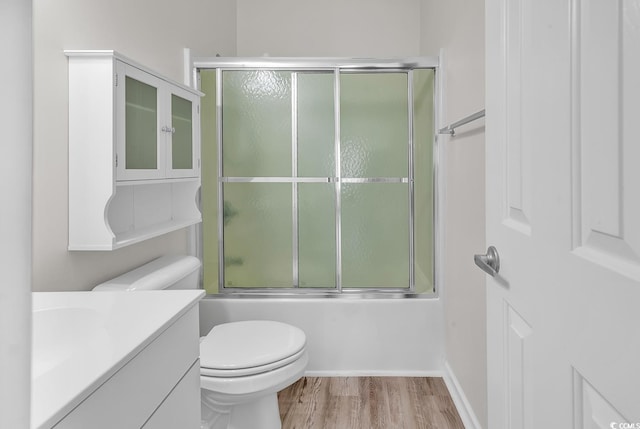 full bathroom featuring toilet, vanity, bath / shower combo with glass door, and hardwood / wood-style floors