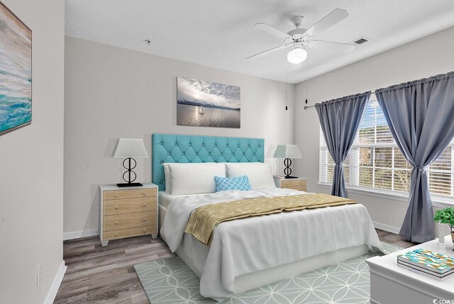 bedroom with a textured ceiling, ceiling fan, and light wood-type flooring